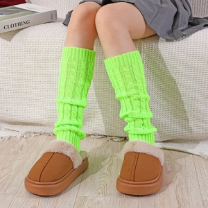 Detail view of neon green cable-knit leg warmers paired with plush platform slippers