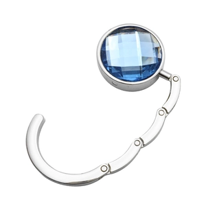 Portable silver metal bag hook with a faceted blue crystal for desktop and mantel