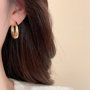 Close-up of thick golden hoop earrings with high-polish finish on female model