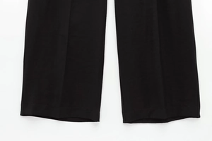 Dettaglio ravvicinato dell'orlo e della trama del tessuto dei pantaloni neri a gamba larga
