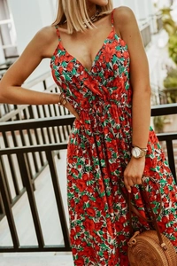 Detail of red floral print on bohemian maxi dress with V-neckline and straw bag accessory