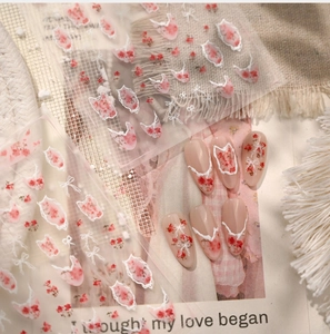 Detailed view of floral nail stickers with white ribbon bows and delicate lace designs