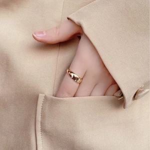 Close-up of a gold dome star ring with zircon stones on a model wearing a beige blazer