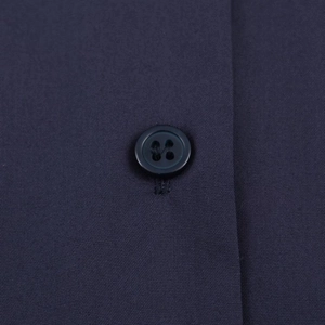 Detailed close-up of navy blue poplin fabric texture and matching resin button on shirt