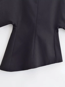 Détail du haut noir avec manches courtes montrant des coutures et un ourlet asymétrique
