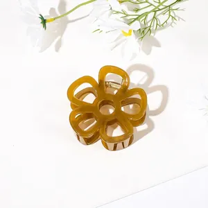 Close-up of translucent amber flower hair claw clip with golden metal spring detail