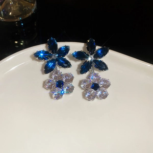 Macro detail of silver tone flower earrings with dark blue marquise and clear zircon stones