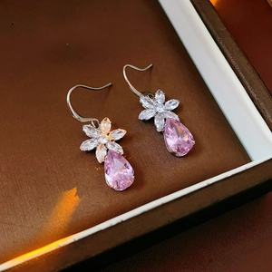 Vue détaillée de boucles d'oreilles fleur avec pierres roses dans un coffret luxe