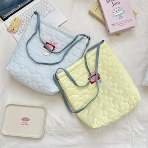 Gros plan de sacs cabas matelassés en forme de cœur en bleu clair et jaune pastel