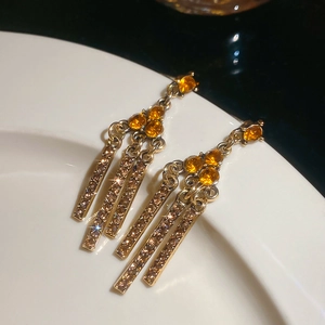 Macro shot of gold vintage earrings with orange gemstones and sparkling champagne tassels