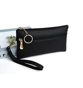 Detail of black lychee grain leather clutch bag with golden hardware and wrist strap