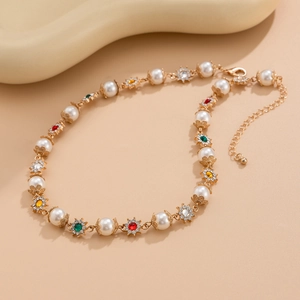 Détails de collier doré avec perles blanches et fleurs colorées en strass brillants