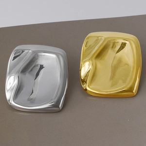 Close-up of irregular wave-textured square earrings in polished gold and silver finish