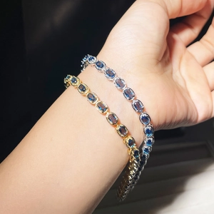 Close-up of gold and silver sapphire style oval stone bracelets on wrist