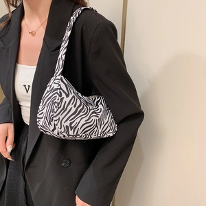 Sac à bandoulière tendance à motif zèbre pour femme porté avec un costume noir