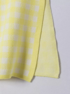 Detailed macro shot of the yellow and cream plaid knitted fabric texture on this outfit