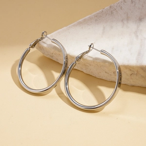 Macro shot of silver hoop earrings with engraved lettering on white textured stone