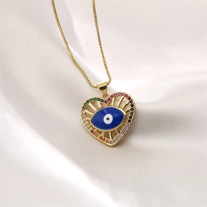 Detailed view of gold heart evil eye pendant with colorful gems on white silk