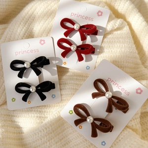 Three velvet pearl bow hair clips in red, black and brown on a princess display card