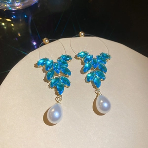 Détail de boucles d'oreilles papillon avec cristaux bleus et une perle en goutte blanche