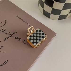 Detail of small checkerboard hair claw clip with gold metal finish on a book