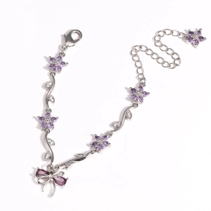 Detail of silver bow bracelet featuring purple flower charms and adjustable lobster clasp
