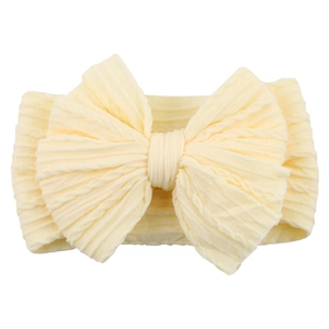 Detail showing soft yellow knit fabric texture and large bow on a baby headband