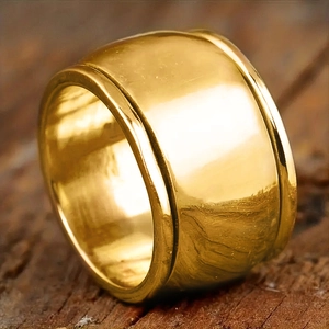 Macro shot of polished wide gold ring with grooved edges on a textured wood surface