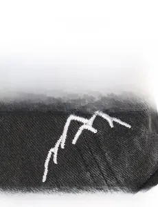 Macro shot of high-quality white mountain embroidery on a black washed cotton baseball cap