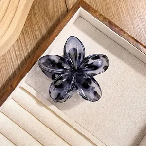 Detail of a dark blue marble resin flower hair claw on a wooden jewelry display