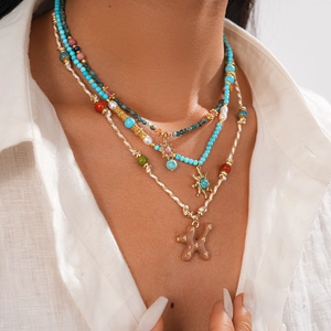 Détail du collier bohème multicouche avec perles turquoise et pendentif soleil doré