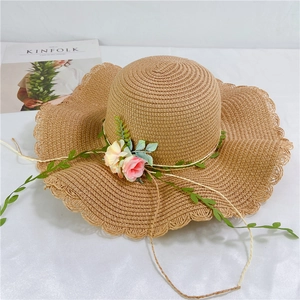 Detail of summer straw hat with pink flowers, wavy brim and Kinfolk magazine backdrop