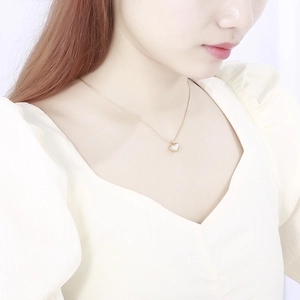 Collier cœur doré en acier inoxydable avec nacre blanche porté par un mannequin