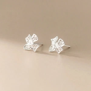 Detailed view of silver bow stud earrings with intricate filigree openwork and texture