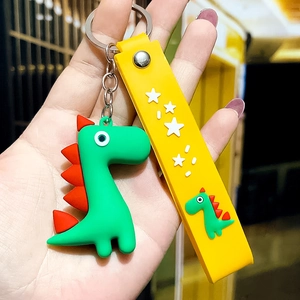 Detail of green cartoon dinosaur keychain with yellow star strap and silver metal clasp