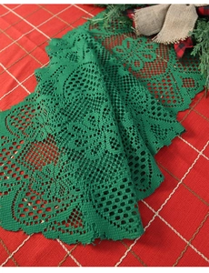 Close-up of green lace Christmas table runner with intricate hollow floral knit patterns