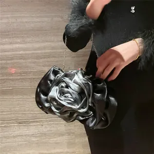 Macro detail of a 3D rose-shaped clutch bag in black leather and silver silk
