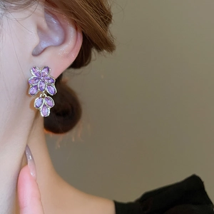 Detail von lila Blumen-Ohrhängern mit Kristallen am Model für einen eleganten Stil