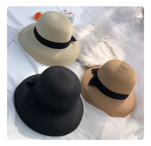 Detail showing beige, brown and black straw hats with black ribbon bows for summer