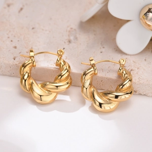 Gold stainless steel twisted hoop earrings with a chunky spiral texture on stone