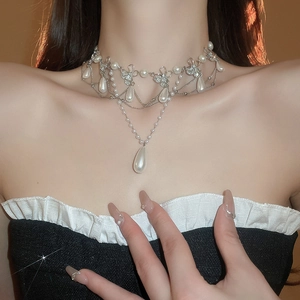 Close-up of a floral rhinestone necklace with a teardrop pearl pendant on a model
