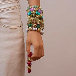 Close-up of stacked acrylic beaded bracelets featuring colorful stones and gold metal accents