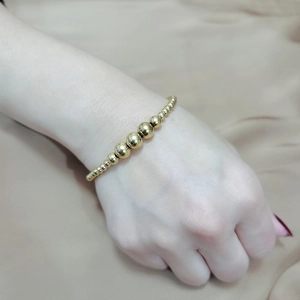 Close-up of golden beaded elastic bracelet with gradient beads on model wrist