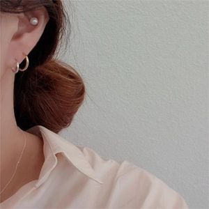 Close-up of elegant gold and silver hoop earrings with a pearl stud on female model