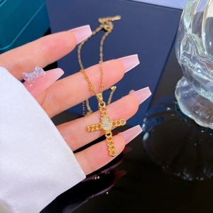 Titanium steel gold cross necklace with zircon inlay held by hand for a luxury look