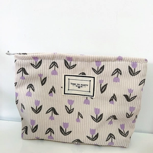 Close-up of beige corduroy makeup bag featuring purple tulip patterns and zipper detail
