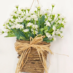 Close-up of white daisy floral arrangement in a woven hanging basket with raffia bow