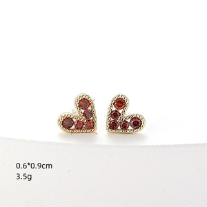 Minimalist gold heart stud earrings with red round gemstone on a clean white background