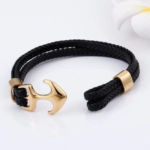 Macro detail of nautical gold anchor clasp on black braided leather bracelet for men