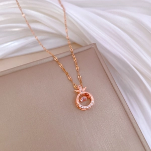 Elegant rose gold Pipa pendant necklace with dancing cubic zirconia on beige jewelry box
